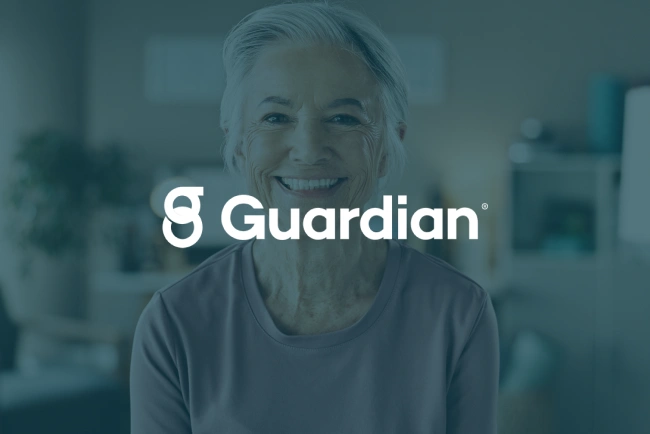Smiling woman in dental office with Guardian logo overlay, professional healthcare setting.