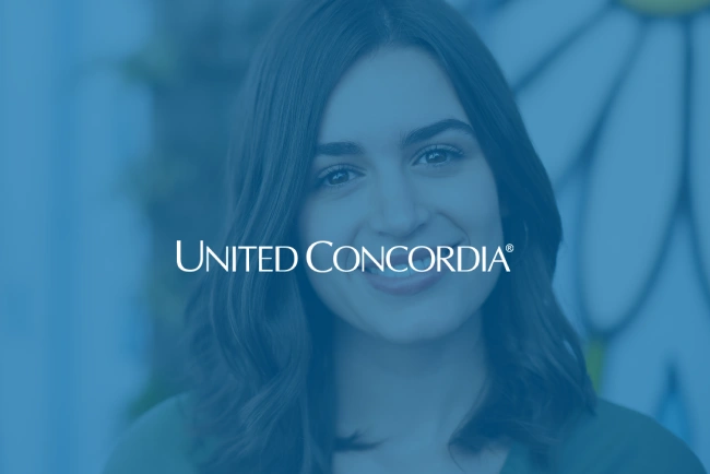 Smiling woman with long dark hair in professional blue-toned setting with United Concordia branding.